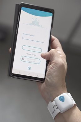 Imagen de la pulsera de geolocalización para el paciente y de la aplicación 'Virtual Waiting Room' para el teléfono del acompañante.