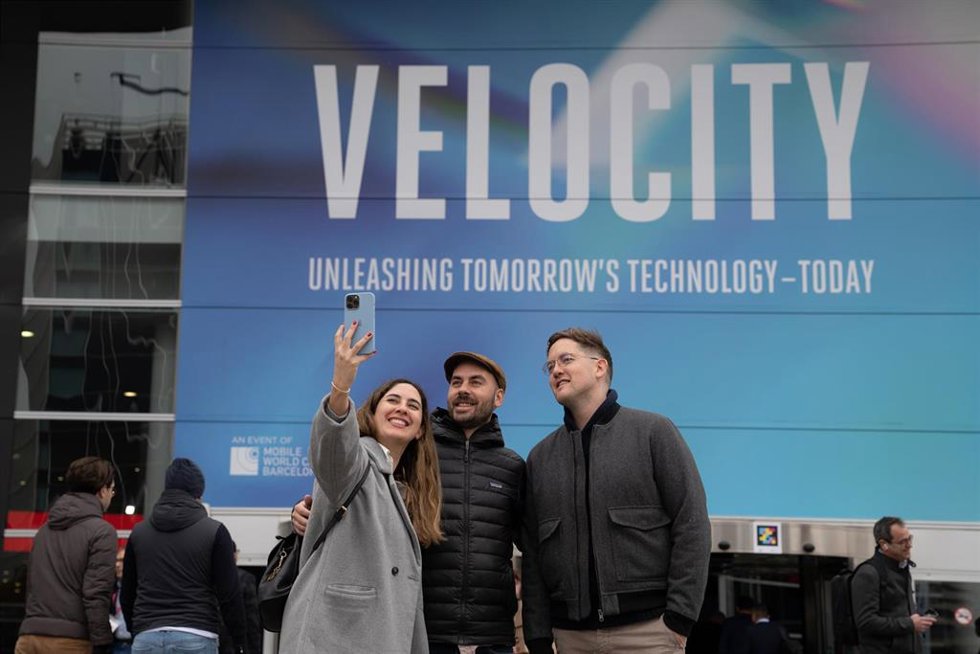 Tres personas se hacen un selfie en una de las entradas del Mobile World Congress (MWC) 2023, a 28 de febrero de 2023, en L'Hospitalet de Llobregat, Barcelona, Catalunya (España). El Mobile de esta edición, donde exponen sus productos y servicios más de