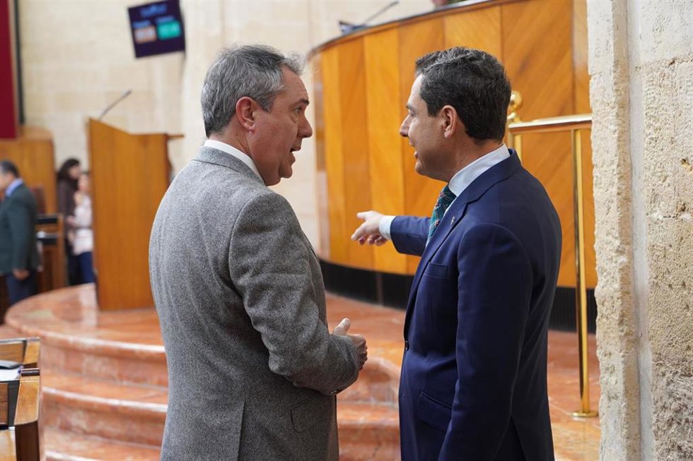 El presidente de la Junta de Andalucía, Juanma Moreno, (d) dialoga con el secretario general del PSOE de Andalucía y presidente del Grupo Parlamentario Socialista, Juan Espadas, (i) en el Pleno del Parlamento. (Foto de archivo).
