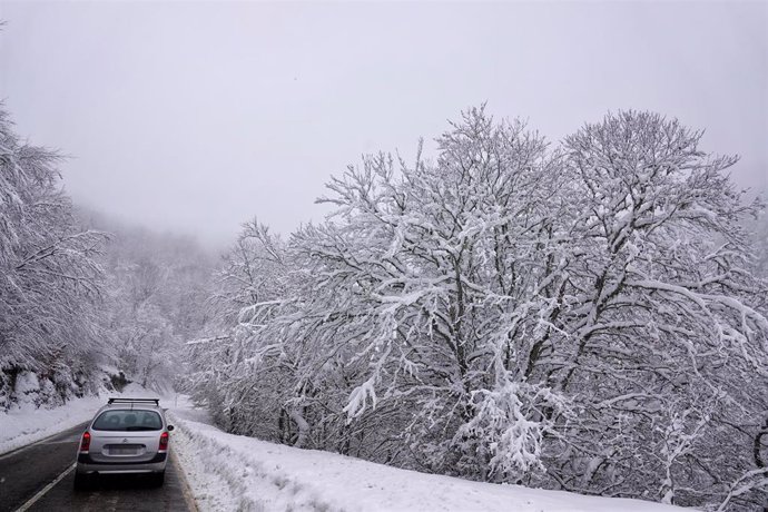 Archivo - Un vehículo sube por una carretera nevada