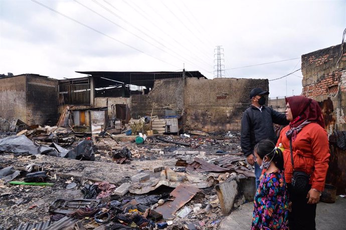 Personas sobre los escombros de las casas dañadas en una zona residencial cerca del lugar de una explosión de un almacén de combustible en Yakarta