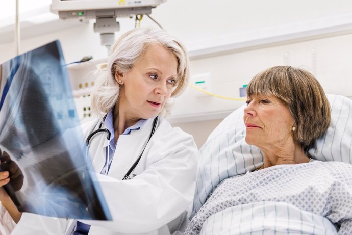 Paciente hospitalizada mirando una radiografía de pulmones.
