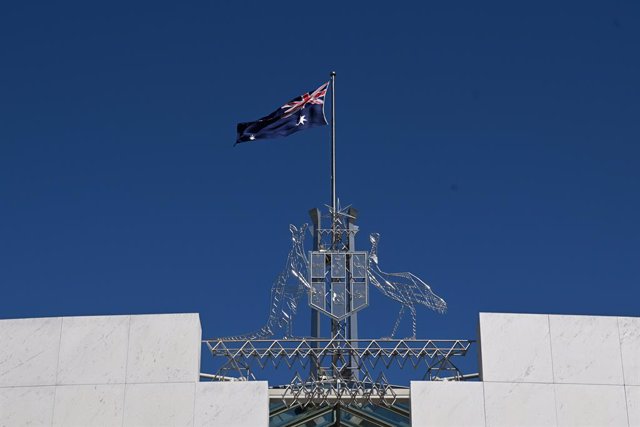 Archivo - La bandera australiana ondeando en la entrada del Parlamento en Canberra.