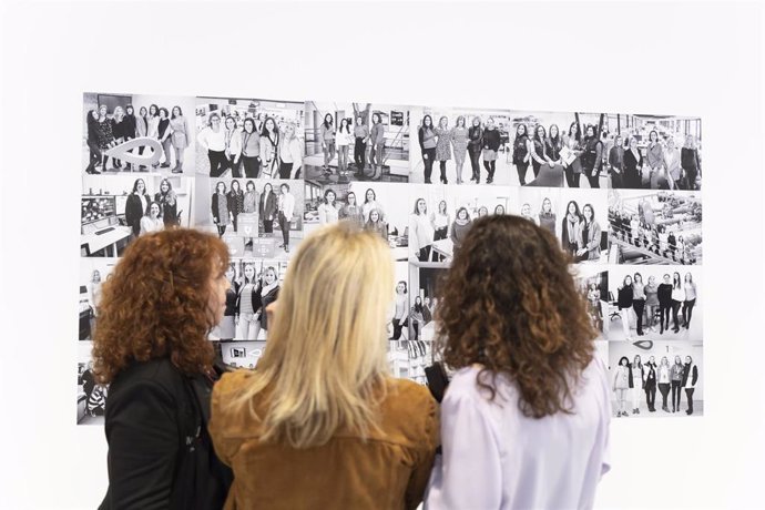 Tres mujeres observan algunas de las fotografías de la segunda edición de la exposición fotográfica Las mujeres del agua. 