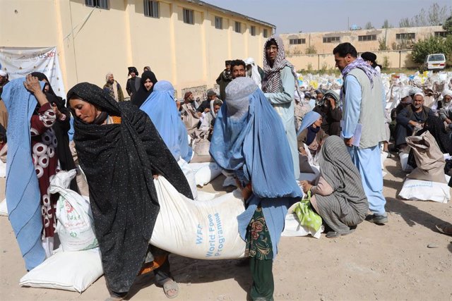 Archivo - Mujeres afganas transportando ayuda humanitaria del PMA
