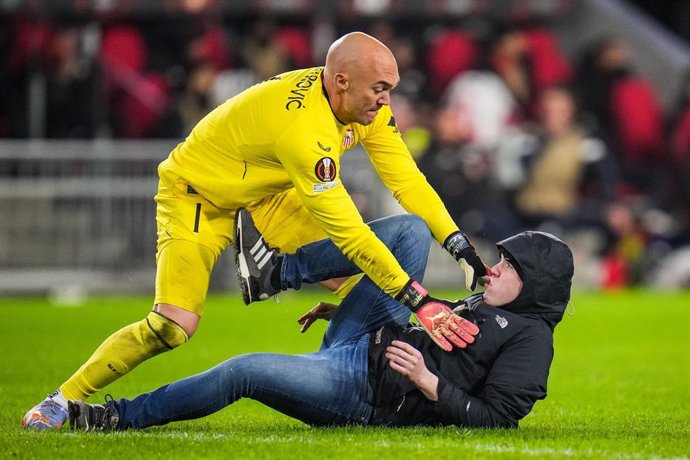 El portero del Sevilla Marko Dmitrovic sostiene a un aficionado del PSV que intenta agredirle. 