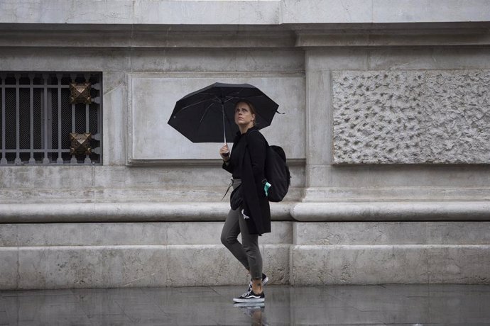 Archivo - Una mujer se protege de la lluvia bajo su paraguas