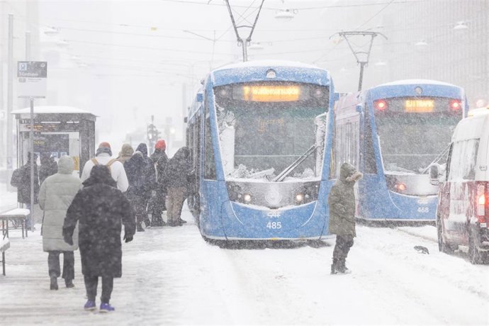 Personas junto a tranvías en Estocolmo (Suecia) tras una nevada