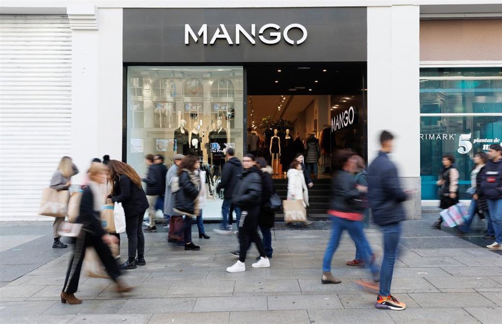 Archivo - Varias personas caminan frente a una tienda de Mango.