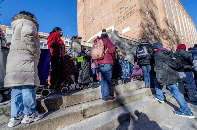 Archivo - Varias personas hacen cola delante de una parroquia para recoger alimentos.