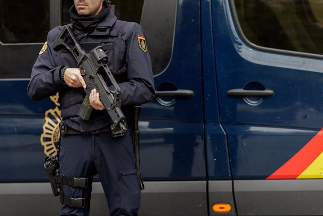 Archivo - Agente de Policía Nacional armado, frente a un furgón policial.