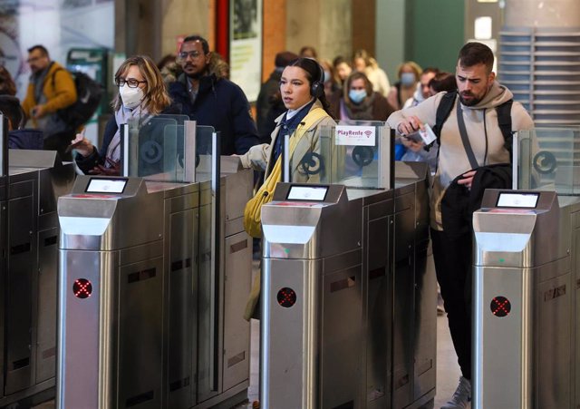 Varias personas con y sin mascarilla pasan los tornos de la estación Puerta de Atocha-Almudena Grandes, a 8 de febrero de 2023, en Madrid (España).