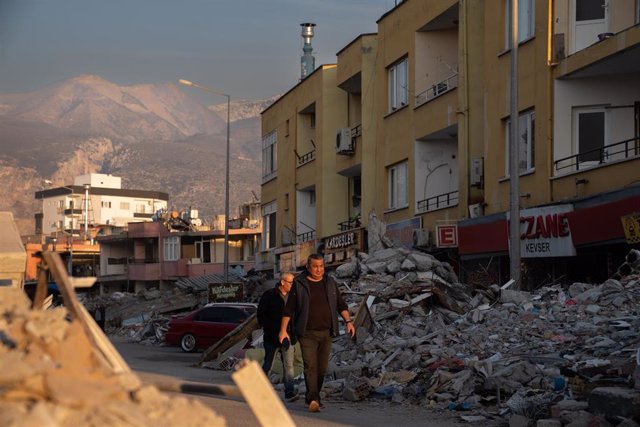 Varias personas caminan por los escombros de los edificios derribados por el terremoto, a 23 de febrero de 2023, en Iskenderun, Turquía