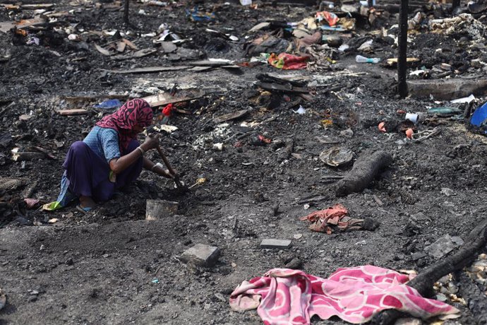 Archivo - 13 June 2021, India, New Delhi: A woman looks for her belongings from the charred remains of the camp following a fire incident that broke out at the Rohingya refugee camp leaving over at least 50 shanties of Rohingya refugees gutted. Photo: A