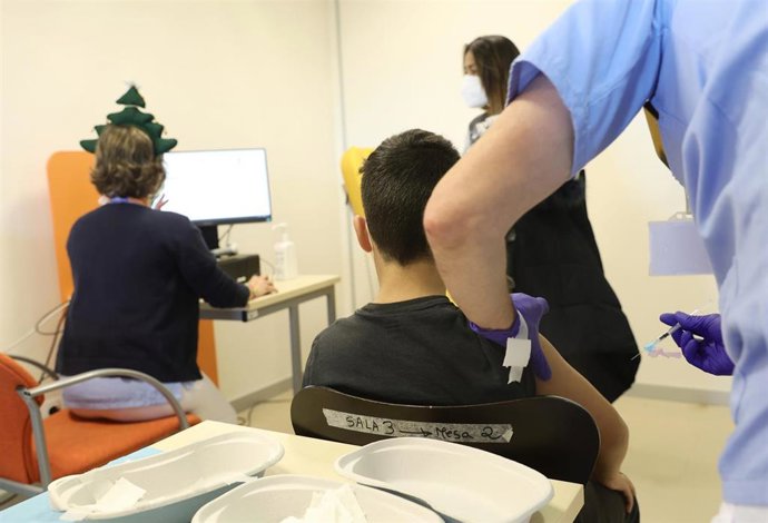 Archivo - Un trabajador sanitario inyecta la vacuna a un menor.