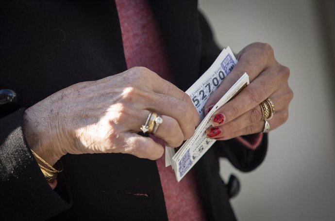 Archivo - Una mujer sostiene dos décimos para el Sorteo Extraordinario del Niño. A 04 de enero de 2023, en Sevilla (Andalucía, España). El Sorteo Extraordinario del Niño celebra su 80 edición coincidiendo con el día de los Reyes Magos. La lotería del N