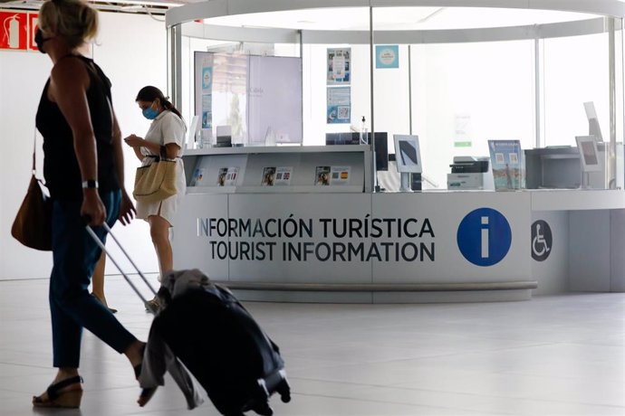 Archivo - Varias personas pasan por delante de la Oficina de Turismo del Aeropuerto Internacional de la Región de Murcia