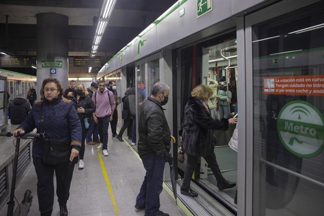 Archivo - Varias personas con y sin mascarillas en la estación de Metro. 