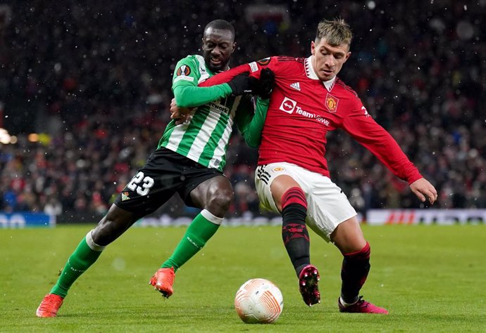 09 March 2023, United Kingdom, Manchester: Manchester United's Lisandro Martinez (R) and Real Betis' Youssouf Sabaly battle for the ball during the UEFA Europa League round of 16 first leg soccer match between Manchester United and Real Betis at Old Tra