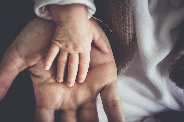 Imagen de una mano de adulto sosteniendo la de un bebé