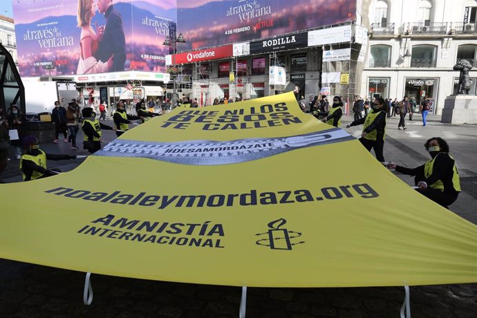 Archivo - Un grupo de personas colocan una lona contra la Ley Mordaza con el lema "Que ni los besos te callen", en la Puerta del Sol, a 10 de febrero de 2022, en Madrid (España). Con esta acción, organizada por Amnistía Internacional, quieren mostrar su