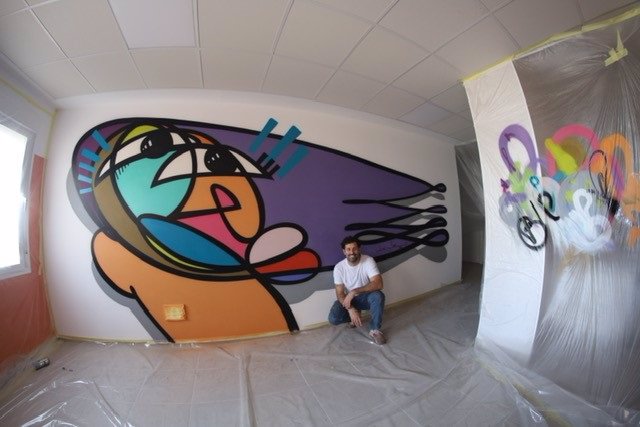 Belin junto a su mural en la sala de espera del Hospital de Día Oncohematológico