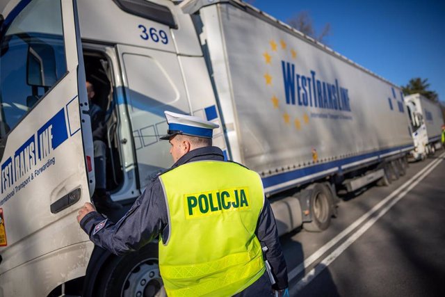 Archivo - Un policía polaco registra un camión en Kusnic, en la frontera con Bielorrusia