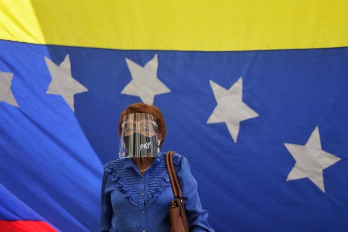Archivo -  Una mujer asiste a una conferencia de la oposición venezolana con una máscara protectora
