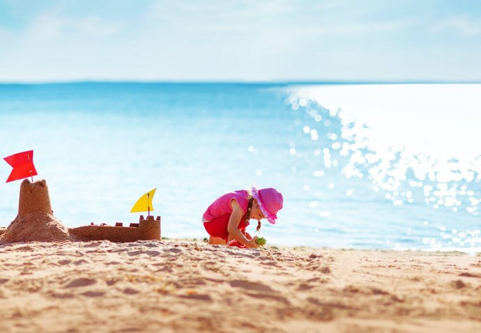 Archivo - Imagen de niña jugando en la playa con castillo de arena