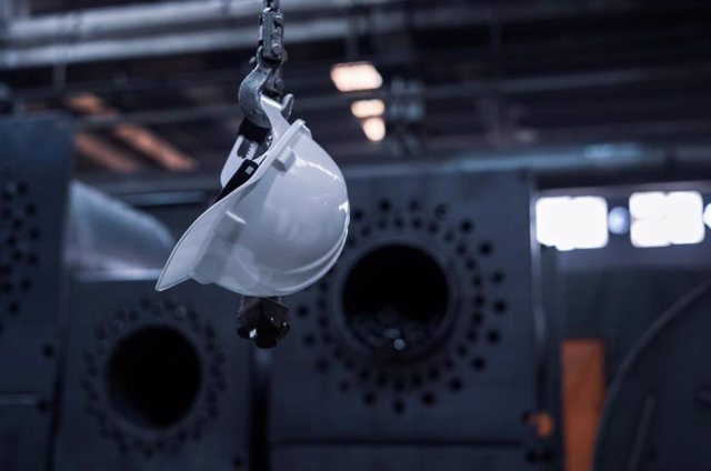 Casco blanco colgado de un gancho en una fábrica