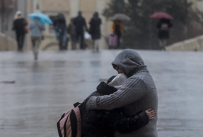 Archivo - Una pareja se abraza mientras llueve en Valncia (8 febrero 2023)