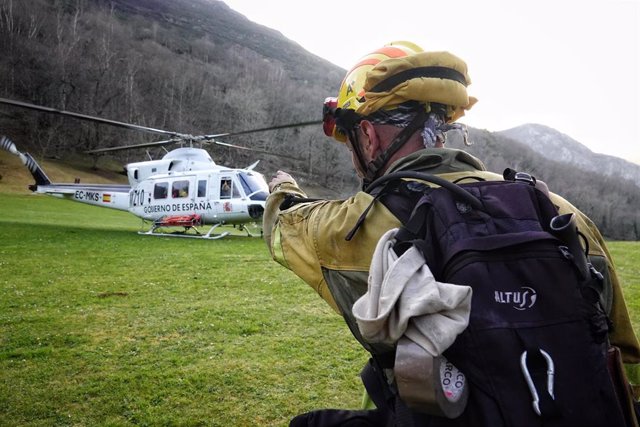 Un bombero de las Brigadas de Refuerzo en Incendios Forestales (BRIF) de Cantabria y un helicóptero trabajan en las labores de extinción de un incendio forestal en el valle de Ardisana, en Llano, Asturias (España). 
