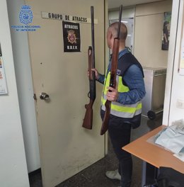 Un agente de la Policía Nacional en Palma sostiene algunas armas intervenidas al detenido.
