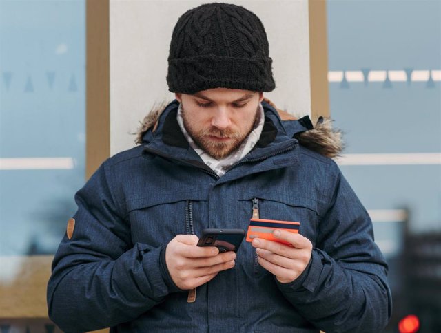 Un usuario utilizando una tarjeta bancaria en su móvil