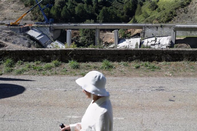 Archivo - Una mujer camina por la carretera mientras se realiza el desmontaje de las pilas 1 y 2 del viaducto de O Castro, en el kilómetro 430 sentido A Coruña de la autovía A-6, en Vega de Valcarce, a 21 de septiembre de 2022, en Vega de Valcarce, León