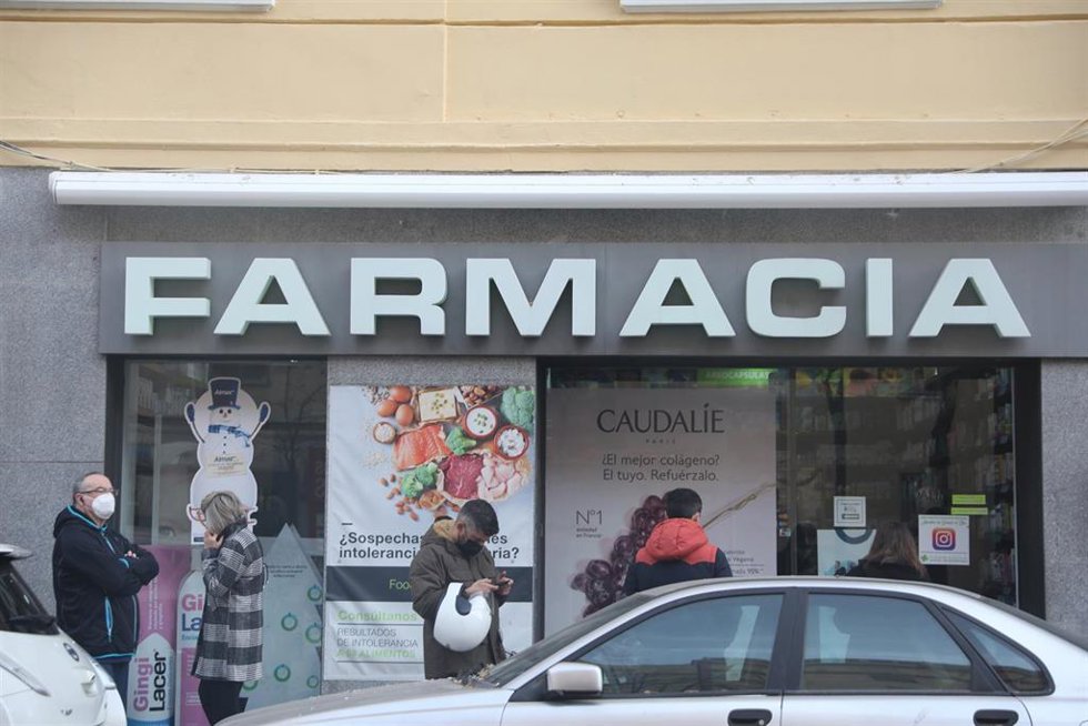 Archivo - Varias personas hacen cola en una farmacia