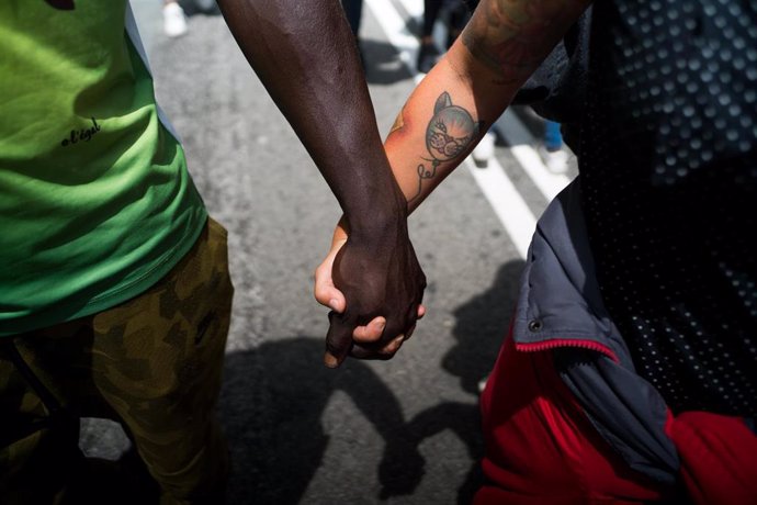 Archivo - Dos personas se dan la mano durante una concentración contra el racismo en Barcelona.