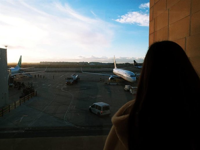 Una pasajera observa desde la terminal varios aviones estacionados en la pista.