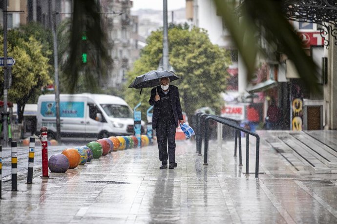 Archivo - Imagen de archivo de un hombre con un paragüas por una calle de Estambul.