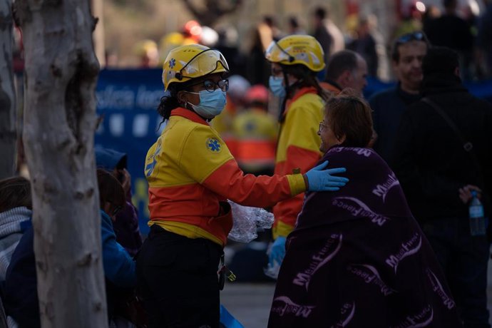 Una professional del Sistema d'Emergncies Mdiques (SEM) atiende a una mujer tras el incendio de una vivienda en Rubí (Barcelona) de este miércoles, en el que han fallecido tres personas