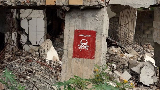 Archivo - Cartel de "Peligro minas" en un colegio destruido por bombardeos de Taiz, Yemen