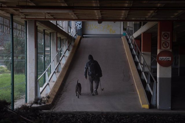 Archivo - Una persona con un perro en un parking abandonado  en Barcelona.