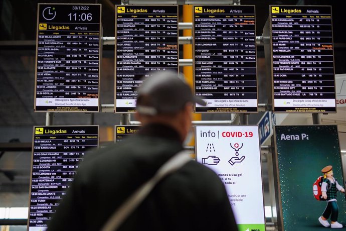 Archivo - Un hombre con mascarilla observa los paneles informativos de las salidas de los vuelos en el aeropuerto Adolfo Suárez Madrid-Barajas, a 30 de diciembre de 2022, en Madrid (España). 