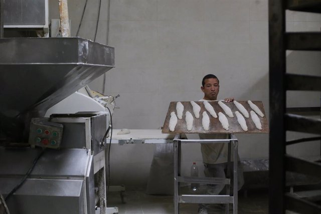 Archivo - Un trabajador prepara barras de pan en un obrador