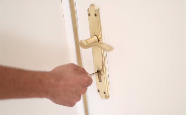 Archivo - Un hombre introduce una llave en la cerradura de la puerta de una vivienda, foto de recurso