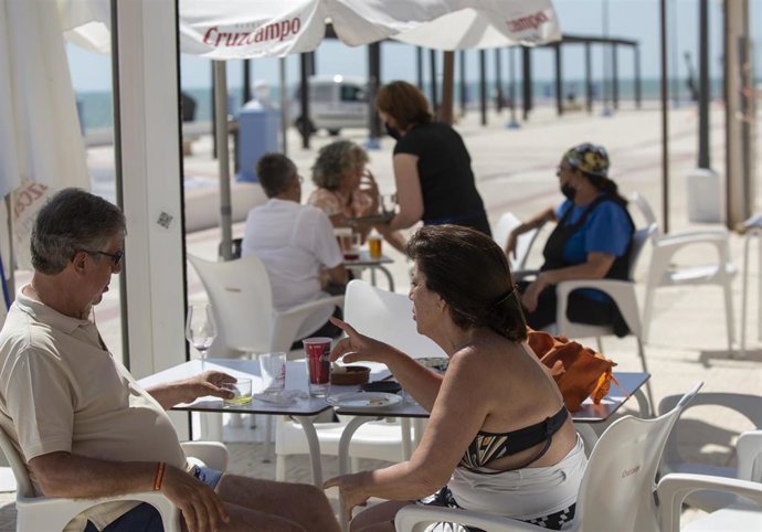 Archivo - Dos personas en un bar del paseo marítimo de la playa de Matalascañas.