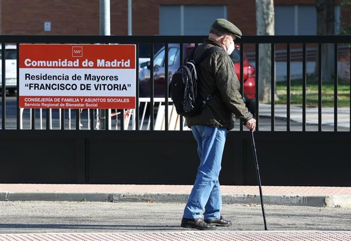 Un señor mayor pasea frente a la residencia de Francisco de Vitoria, a 13 de marzo de 2023, en Alcalá de Henares, Madrid (España).