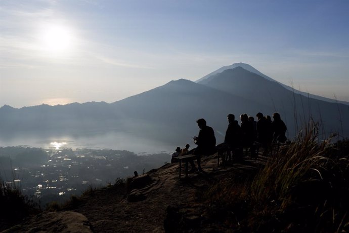 Archivo - October 18, 2019, Bali, Indonesia: The silhouette of a group of hikers relaxing at the summit of Mount Batur in Bali during the sunrise..Every day hundreds of people climb Mount Batur to watch the sunrise. Mount Batur is an active volcano loca