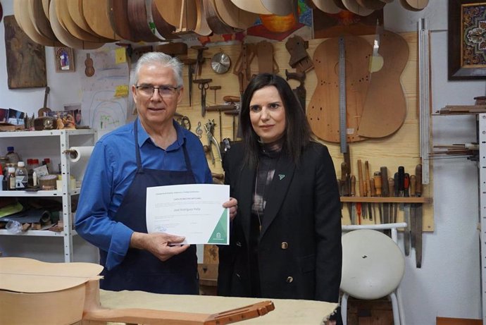 El luthier José Rodríguez Peña recibe la carta de maestro artesano de manos de la delegada de Empleo, María Dolores Gálvez.