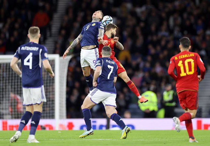28 March 2023, United Kingdom, Glasgow: Scotland's Lyndon Dykes and Spain's Inigo Martinez battle for the ball during the UEFA Euro 2024 qualifying group A soccer match between Scotland and Spain at Hampden Park. Photo: Steve Welsh/PA Wire/dpa